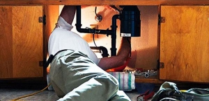 Kernersville Plumber working under a kitchen sink